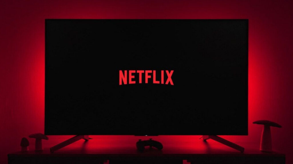 Kırmızı loş ışıkta bir televizyon ve televizyon ekranında Netflix logosu