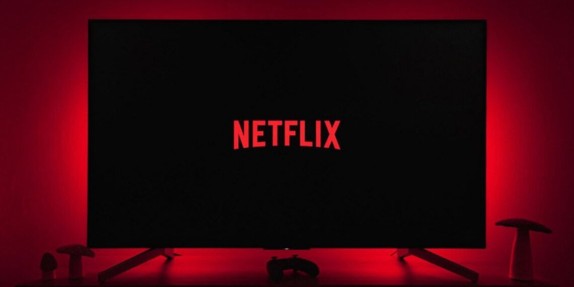 Kırmızı loş ışıkta bir televizyon ve televizyon ekranında Netflix logosu