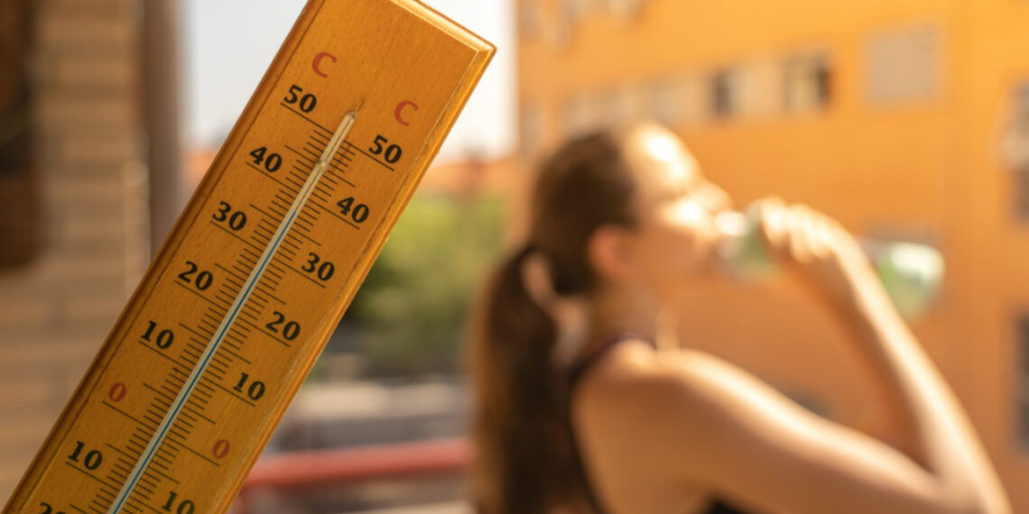 Sıcaklığı gösteren bir termometre ve arkada su içen kadın